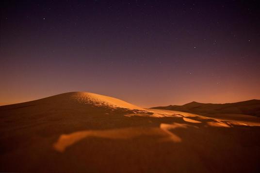 Sand dune after sunset against starry sky