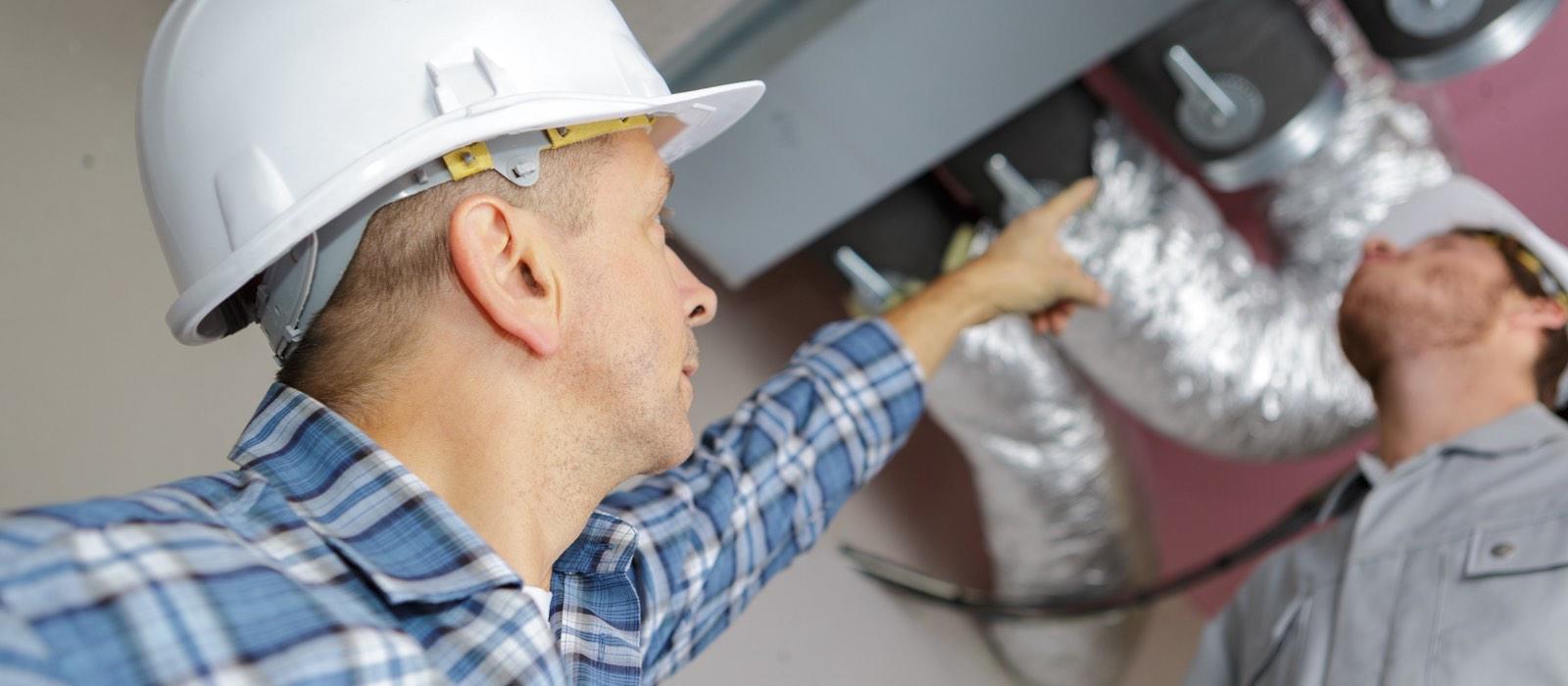 Man wearing hard hat pointing at AC ducts